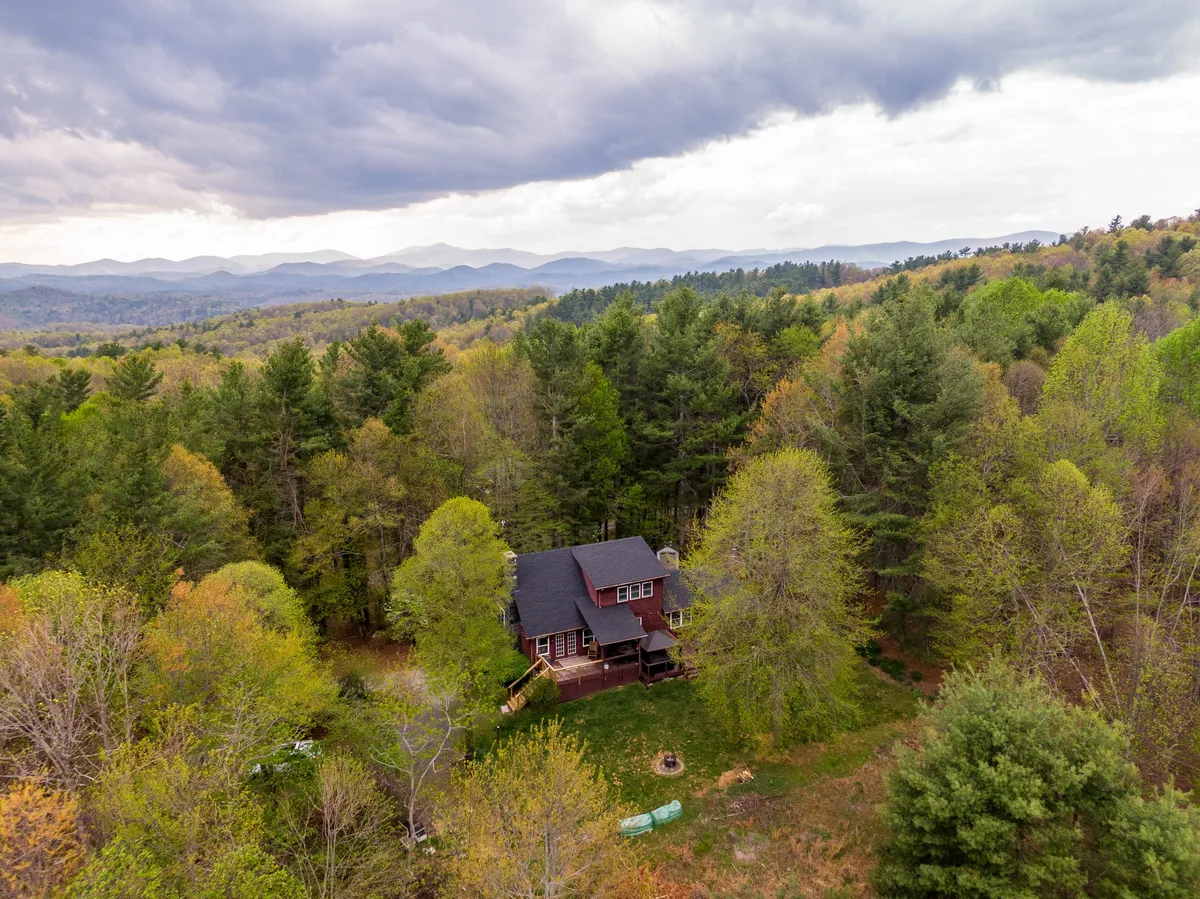 The house is nestled among trees with a stunning mountain backdrop. The expansive natural surroundings offer opportunities for hiking and nature walks right from the doorstep.